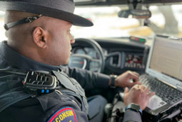 State Patrol trooper sits in vehicle typing on a computer; Wisconsin State Patrol