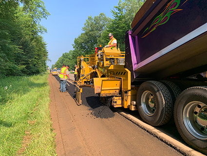 Construction workers pave the shoulder of the Camp 14 Road.