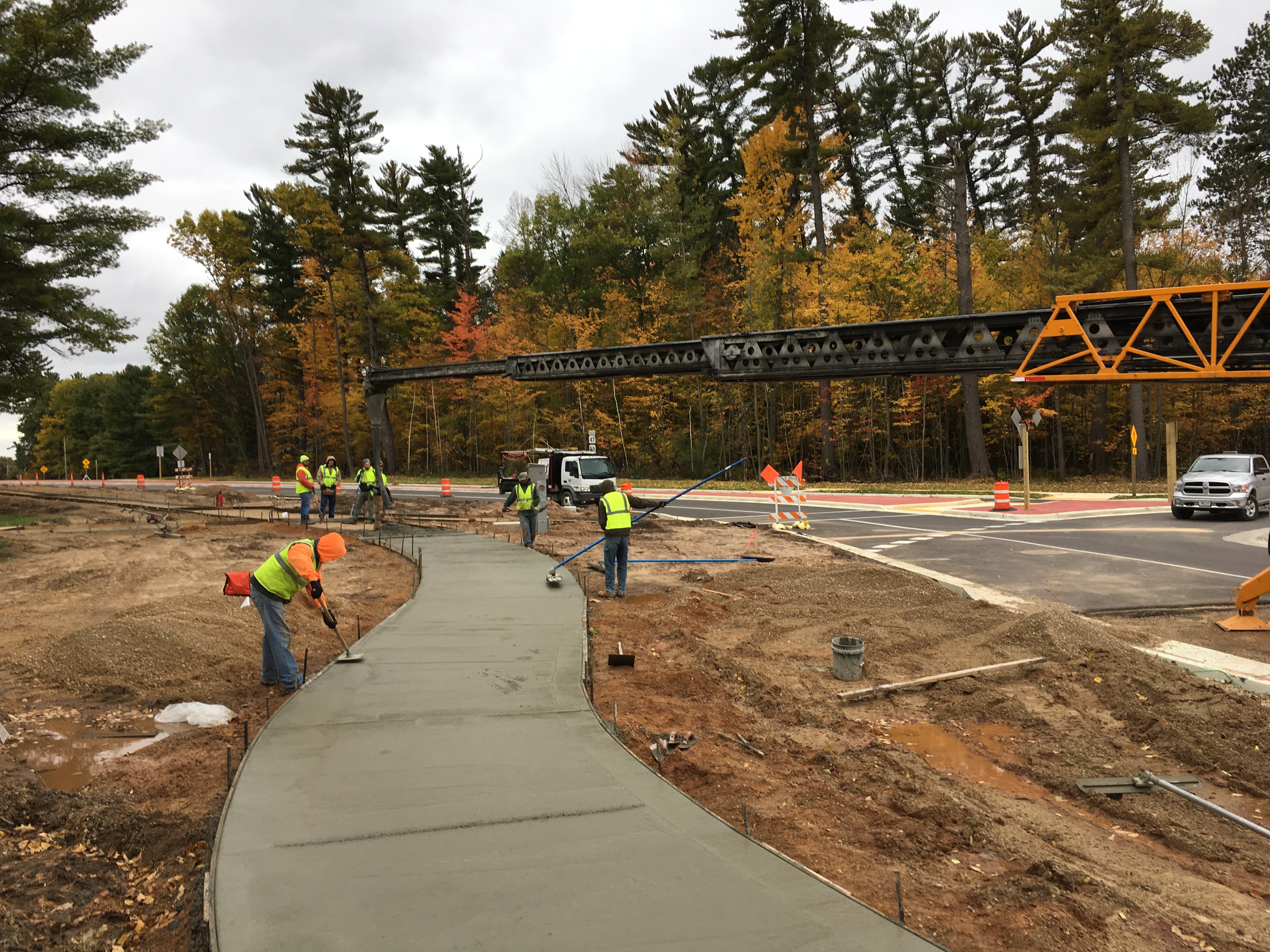 Construction workers are working on a recently poured sidewalk.