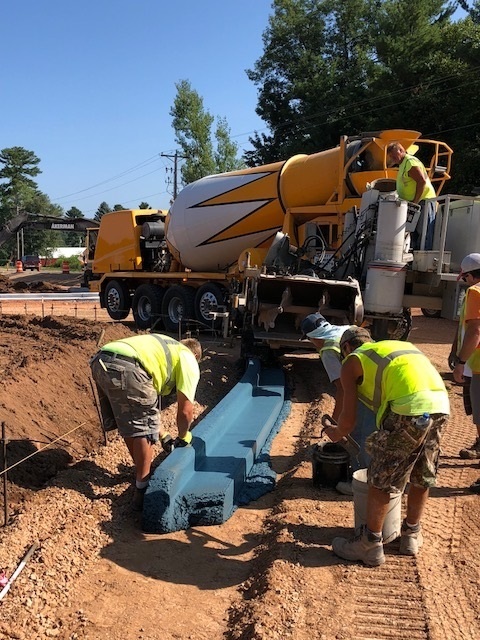 Five people are working behind a yellow and white cement truck.