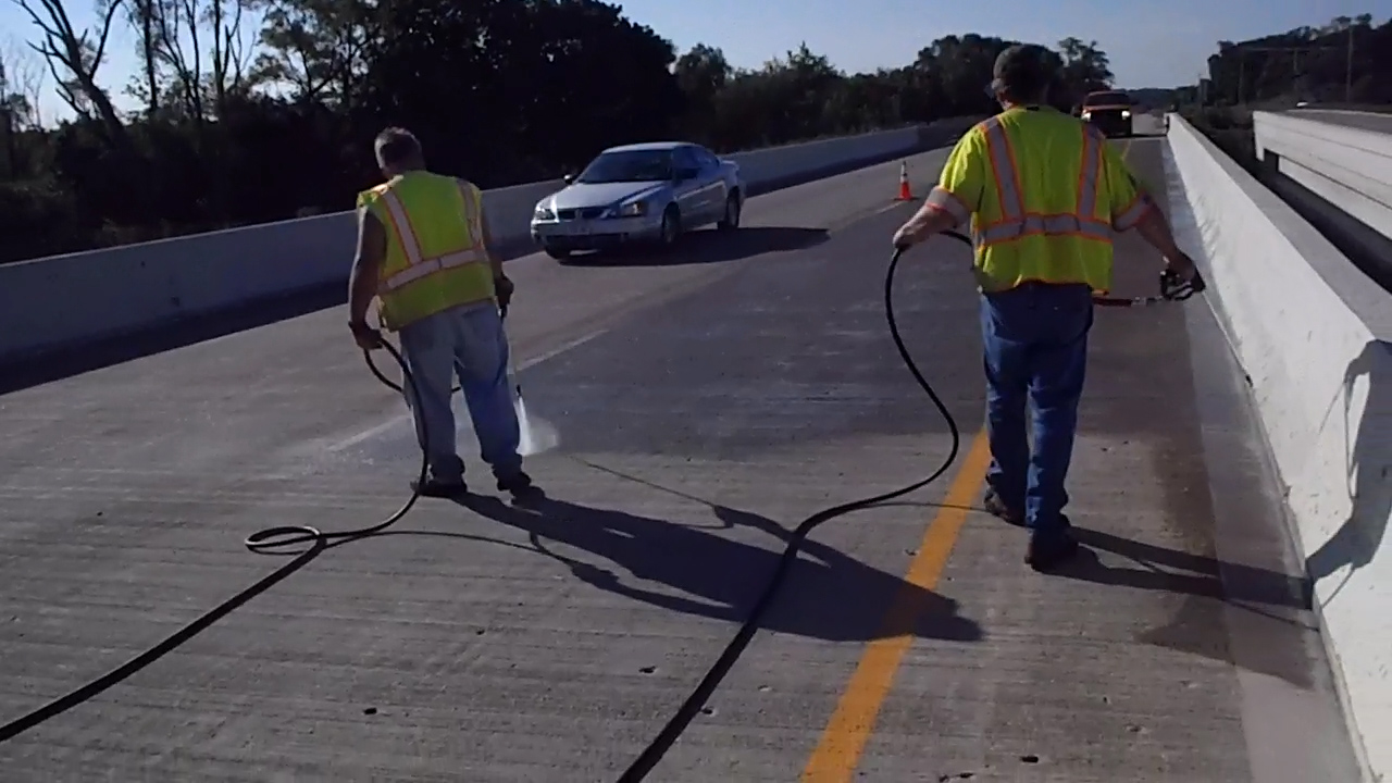 workers sealing a bridge deck with hoses