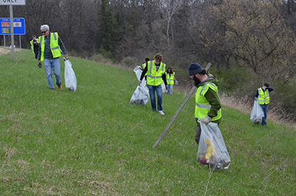 A volunteer wearing a safety vest cleans up a piece of wood.