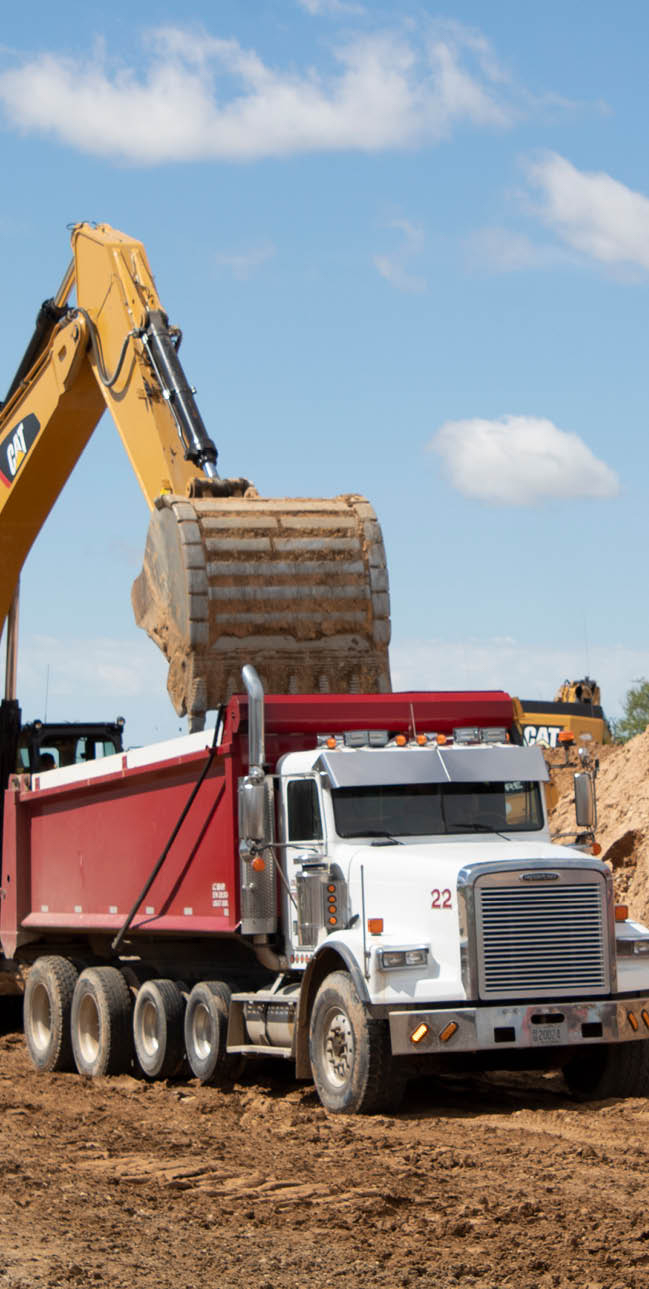 A yellow backhoe and a red and white dump truck.