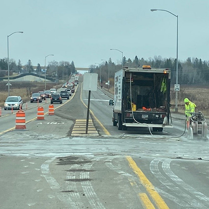 Roadway with traffic, orange barrells are placed in the turn lane and it is closed to traffic.